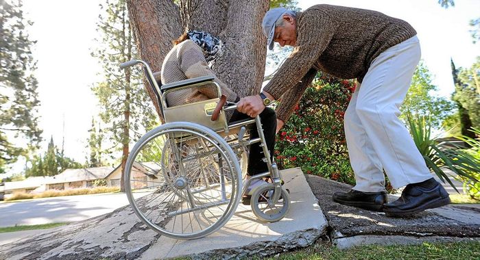 Elderly couple trying to get past a broken sidewalk